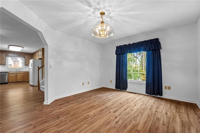 unfurnished room with a chandelier and light hardwood / wood-style flooring