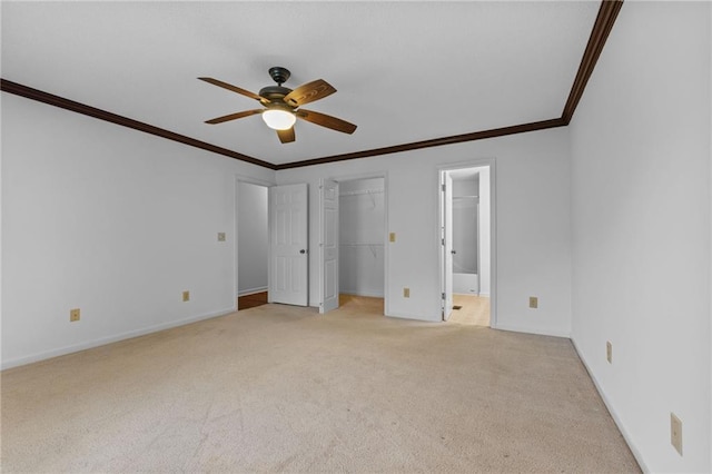 unfurnished bedroom featuring ensuite bath, light carpet, ceiling fan, ornamental molding, and a walk in closet