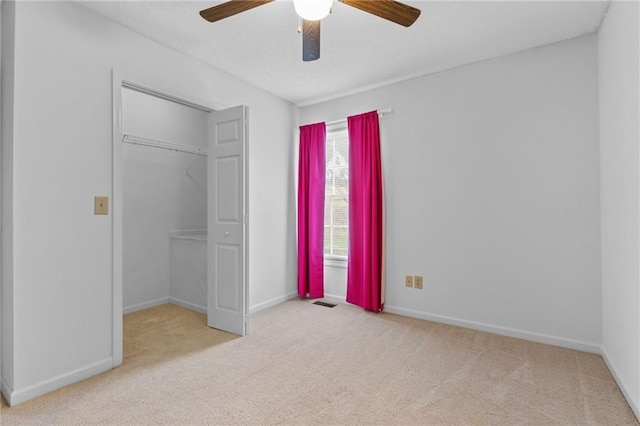 unfurnished bedroom with light carpet, a closet, and ceiling fan