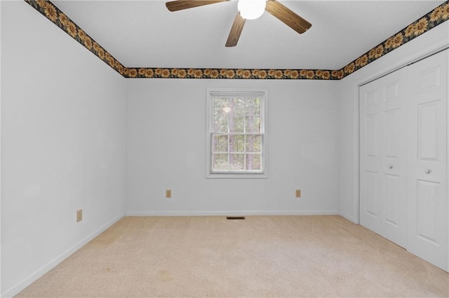 unfurnished bedroom with ceiling fan, light colored carpet, and a closet