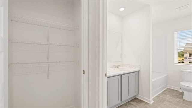 bathroom with toilet, vanity, and a spacious closet