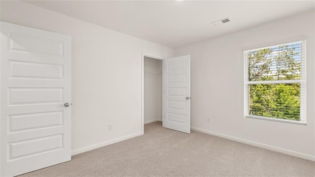 unfurnished bedroom featuring light colored carpet, multiple windows, baseboards, and a closet