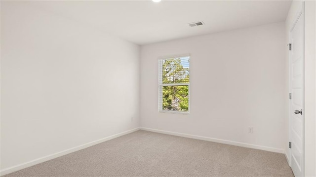 empty room featuring baseboards and light carpet