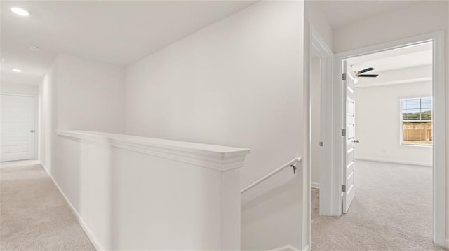 corridor with light colored carpet, baseboards, recessed lighting, and an upstairs landing