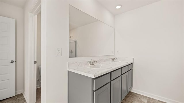 bathroom with double vanity, baseboards, and toilet