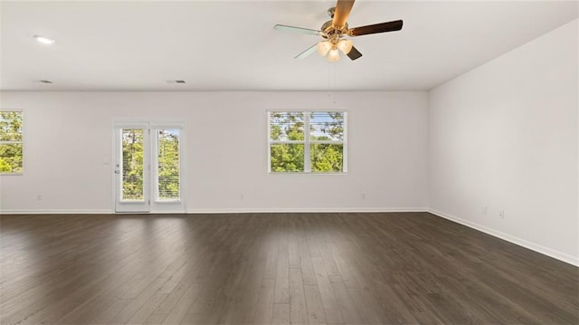 spare room featuring healthy amount of natural light, baseboards, and dark wood finished floors
