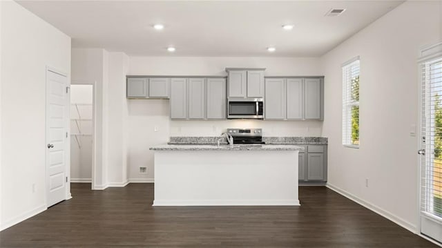 kitchen with stainless steel appliances, gray cabinetry, dark wood-style flooring, a center island with sink, and recessed lighting