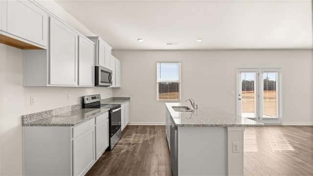 kitchen featuring stainless steel appliances, a sink, dark wood-type flooring, light stone counters, and baseboards