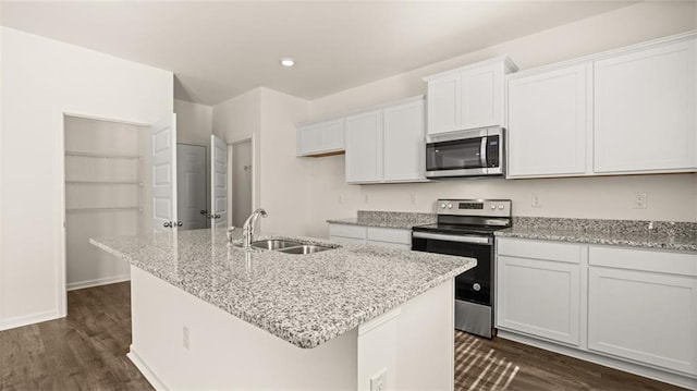 kitchen featuring stainless steel appliances, a sink, a center island with sink, dark wood-type flooring, and white cabinetry