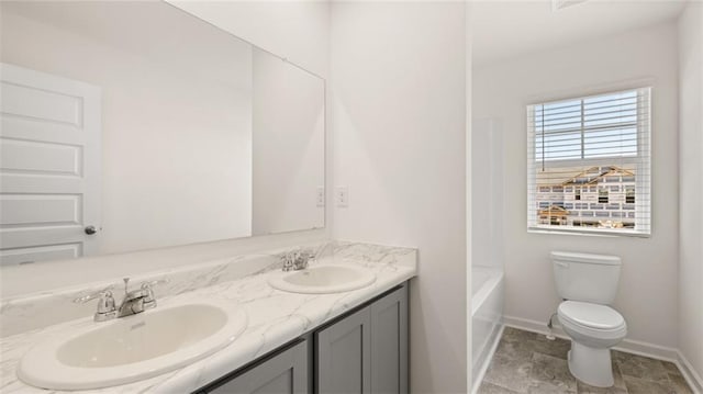 full bathroom with toilet, double vanity, and baseboards