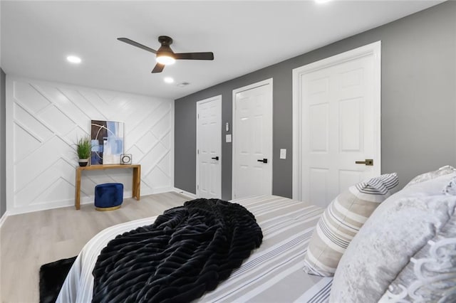 bedroom with ceiling fan, light hardwood / wood-style floors, and multiple closets