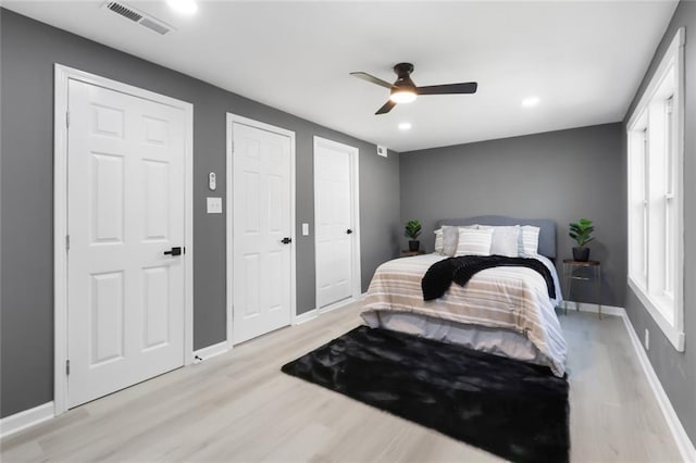 bedroom with multiple closets, ceiling fan, and light hardwood / wood-style floors