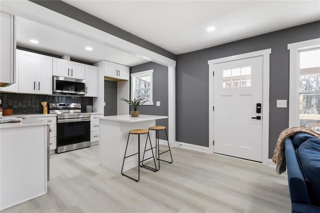 kitchen with stainless steel appliances, white cabinets, decorative backsplash, and plenty of natural light