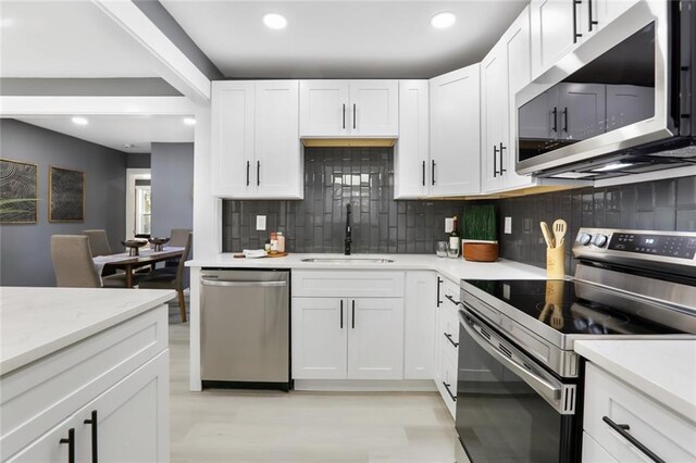 kitchen featuring stainless steel appliances, white cabinetry, tasteful backsplash, and sink