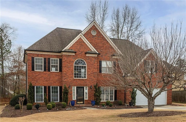 view of front of home featuring an attached garage, brick siding, fence, driveway, and roof with shingles