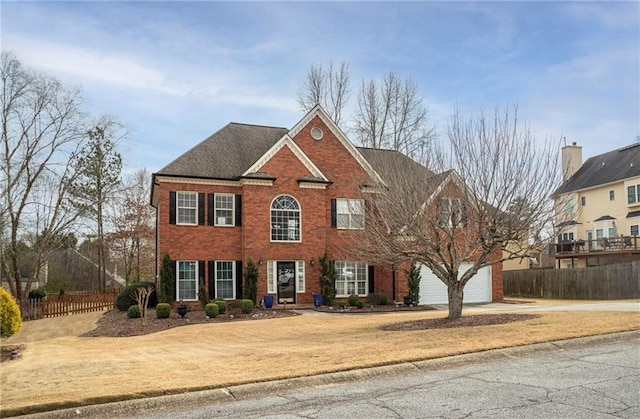 colonial-style house with brick siding, fence, and driveway