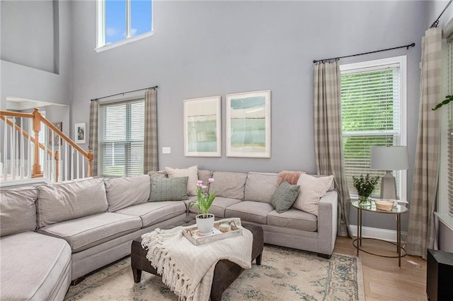 living room featuring a healthy amount of sunlight, a high ceiling, light wood finished floors, and stairs
