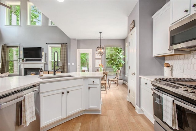 kitchen with decorative backsplash, light countertops, white cabinets, a sink, and stainless steel appliances