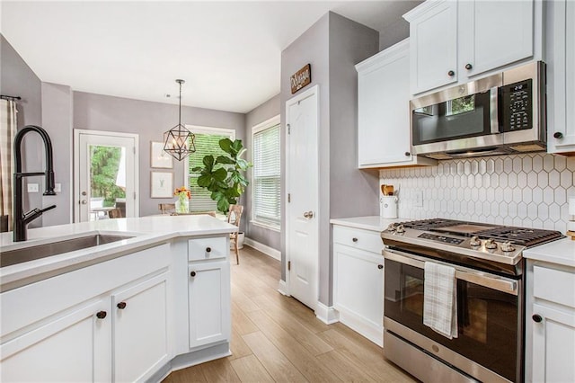 kitchen with baseboards, light countertops, a sink, appliances with stainless steel finishes, and backsplash