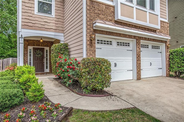 property entrance with fence, driveway, stone siding, and a garage