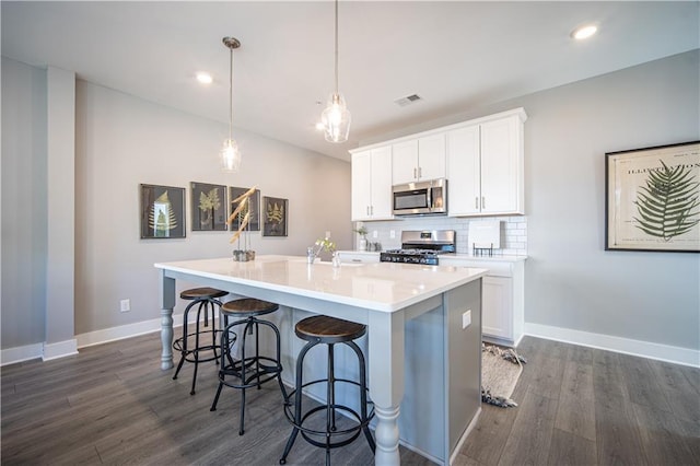 kitchen with dark hardwood / wood-style floors, a center island with sink, pendant lighting, range, and backsplash