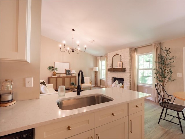 803 Plantation Ridge Overlook, Woodstock, GA 30188 - kitchen featuring a sink, a chandelier, white cabinetry, light wood-type flooring, and a stone fireplace