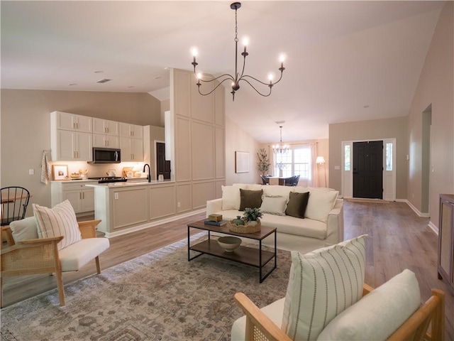 803 Plantation Ridge Overlook, Woodstock, GA 30188 - living room featuring a chandelier, vaulted ceiling, light wood-type flooring, and baseboards
