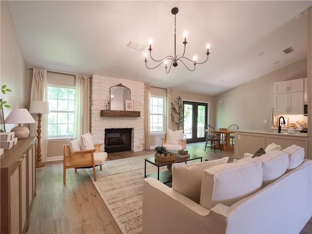 803 Plantation Ridge Overlook, Woodstock, GA 30188 - living area featuring lofted ceiling, light wood finished floors, a chandelier, a stone fireplace, and baseboards