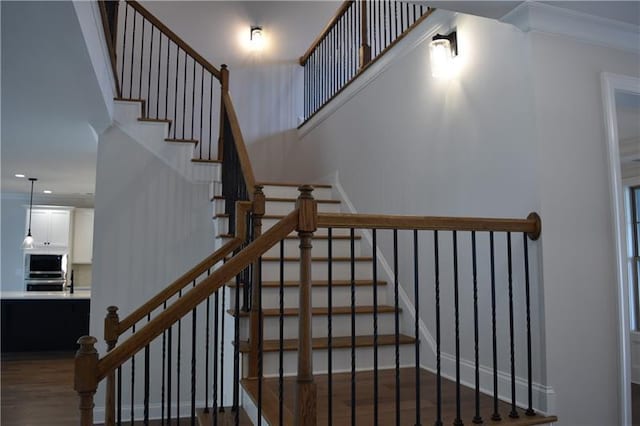 staircase with hardwood / wood-style floors and ornamental molding