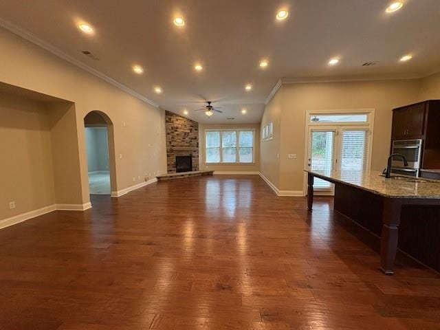 430 La Perla Dr, Sugar Hill, GA 30518 - unfurnished living room with a ceiling fan, crown molding, a fireplace, dark wood-type flooring, and arched walkways