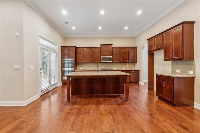430 La Perla Dr, Sugar Hill, GA 30518 - kitchen with stainless steel appliances, ornamental molding, tasteful backsplash, arched walkways, and wood finished floors