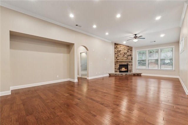 430 La Perla Dr, Sugar Hill, GA 30518 - unfurnished living room featuring ceiling fan, arched walkways, wood finished floors, ornamental molding, and a stone fireplace