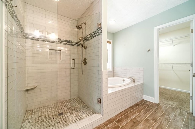 full bathroom featuring wood finish floors, a spacious closet, a garden tub, and a shower stall
