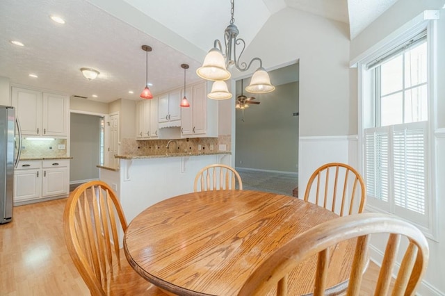 dining room with lofted ceiling, a ceiling fan, recessed lighting, light wood finished floors, and wainscoting