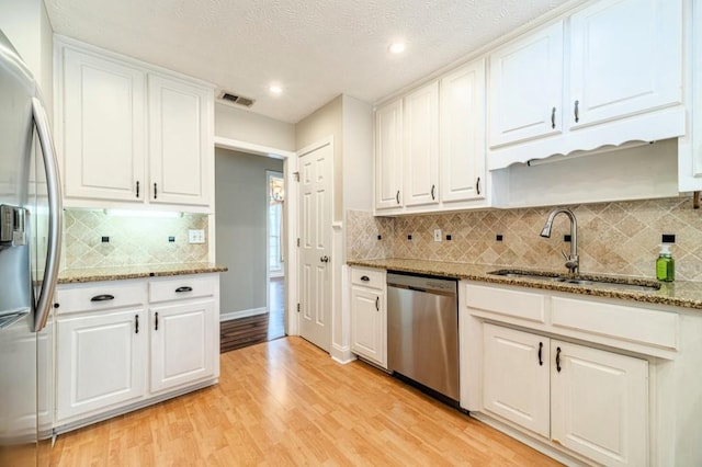 kitchen with light wood-style floors, white cabinets, appliances with stainless steel finishes, and a sink