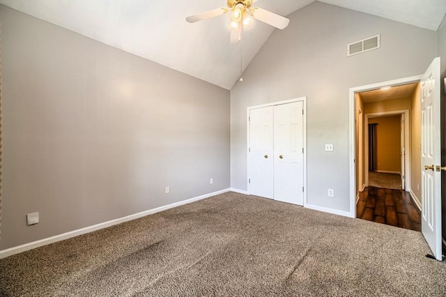 unfurnished bedroom featuring high vaulted ceiling, a closet, dark carpet, visible vents, and baseboards