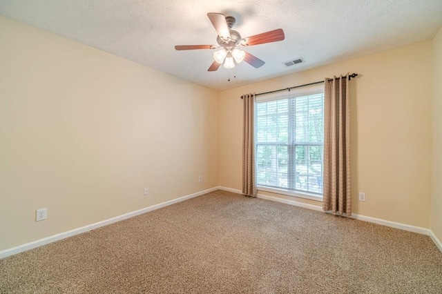carpeted spare room with ceiling fan, a textured ceiling, baseboards, and visible vents