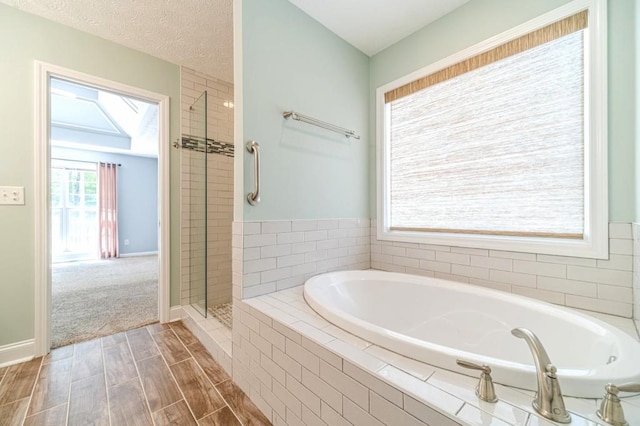 bathroom with a shower stall, baseboards, a garden tub, and wood finished floors