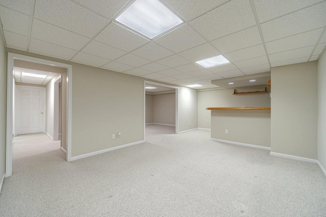 finished basement featuring baseboards, a drop ceiling, and carpet floors