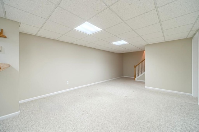 finished below grade area featuring stairway, carpet floors, baseboards, and a drop ceiling