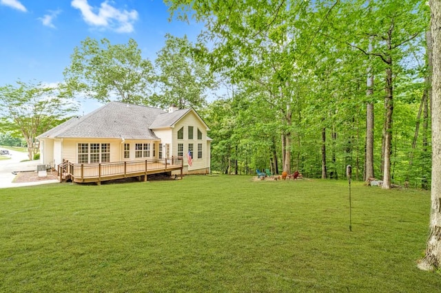 back of house featuring a deck, a chimney, and a lawn