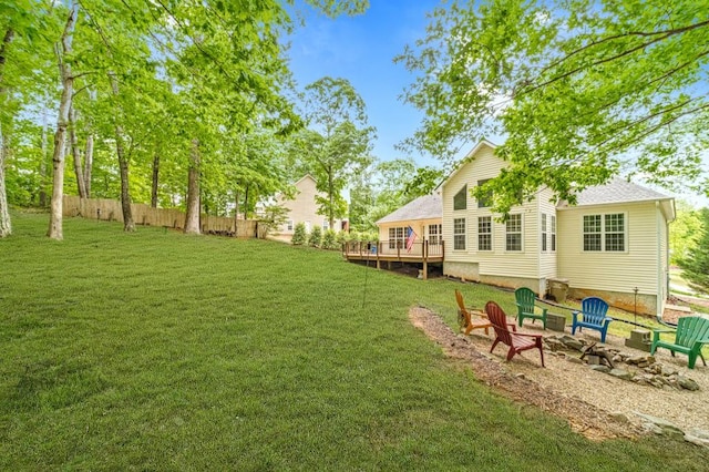 view of yard featuring a deck, a fire pit, and fence