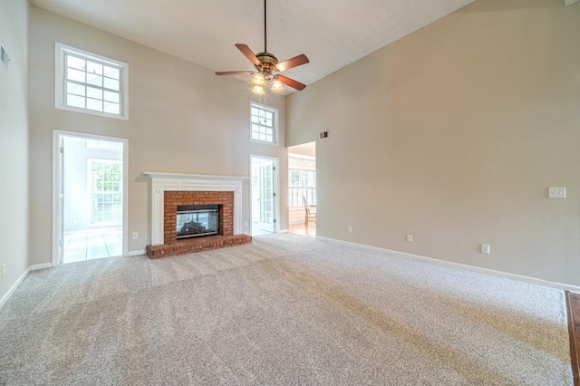 unfurnished living room with a ceiling fan, carpet, baseboards, a towering ceiling, and a fireplace
