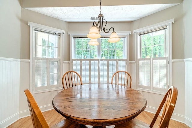dining room featuring light wood-style flooring, a wealth of natural light, a notable chandelier, and visible vents