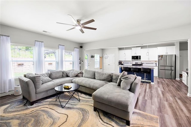 living area with a ceiling fan, wood finished floors, and visible vents
