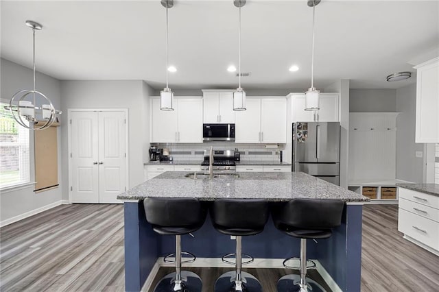kitchen featuring a sink, tasteful backsplash, stainless steel appliances, and light wood-style flooring