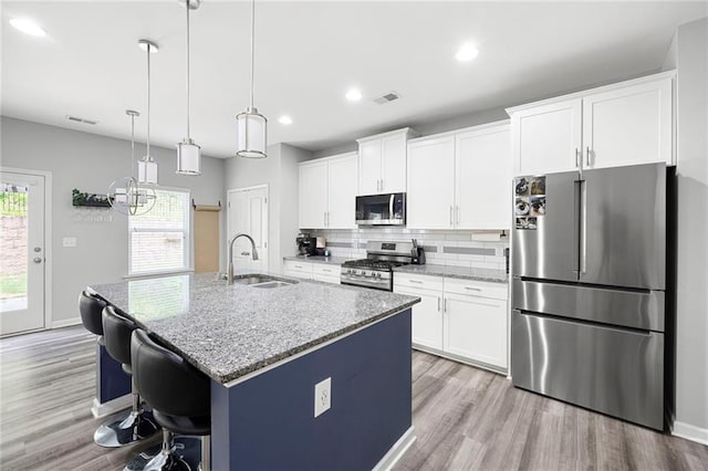 kitchen with visible vents, a kitchen island with sink, a sink, light wood finished floors, and stainless steel appliances