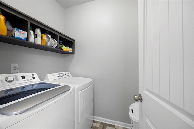 clothes washing area with baseboards, laundry area, and washing machine and clothes dryer