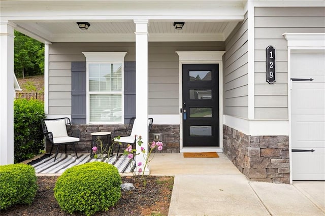 view of exterior entry with covered porch and stone siding