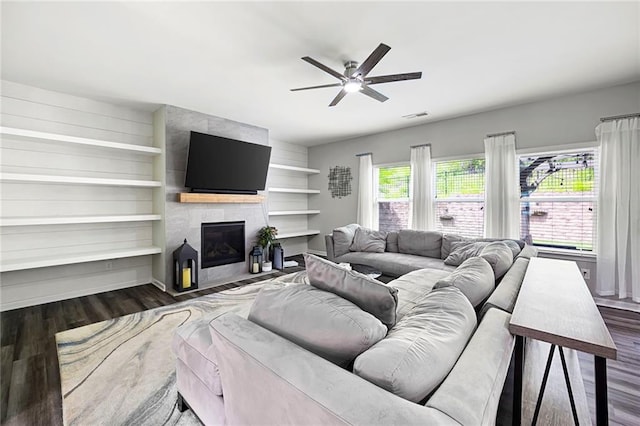 living area with a ceiling fan, visible vents, plenty of natural light, and dark wood-type flooring